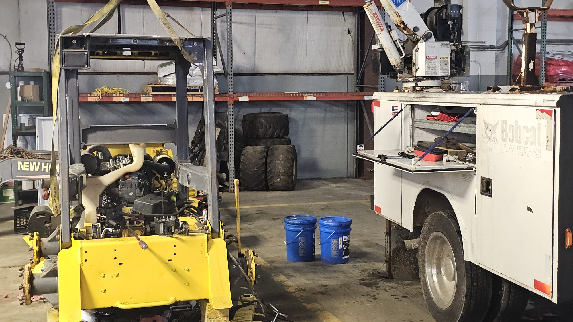 Yellow forklift and white truck in a warehouse setting with tools and equipment.